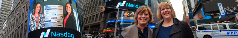 Nancy Beaumont and Judy Beck in Times Square, New York City. NASDAQ screen shows Kaitlin Nolte and Tasha Peltier.
