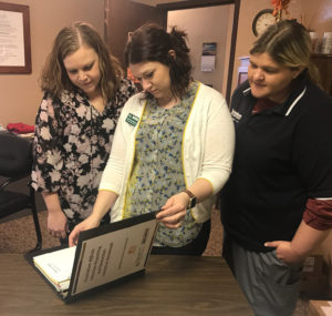 Three staff reviewing a binder of reporting data